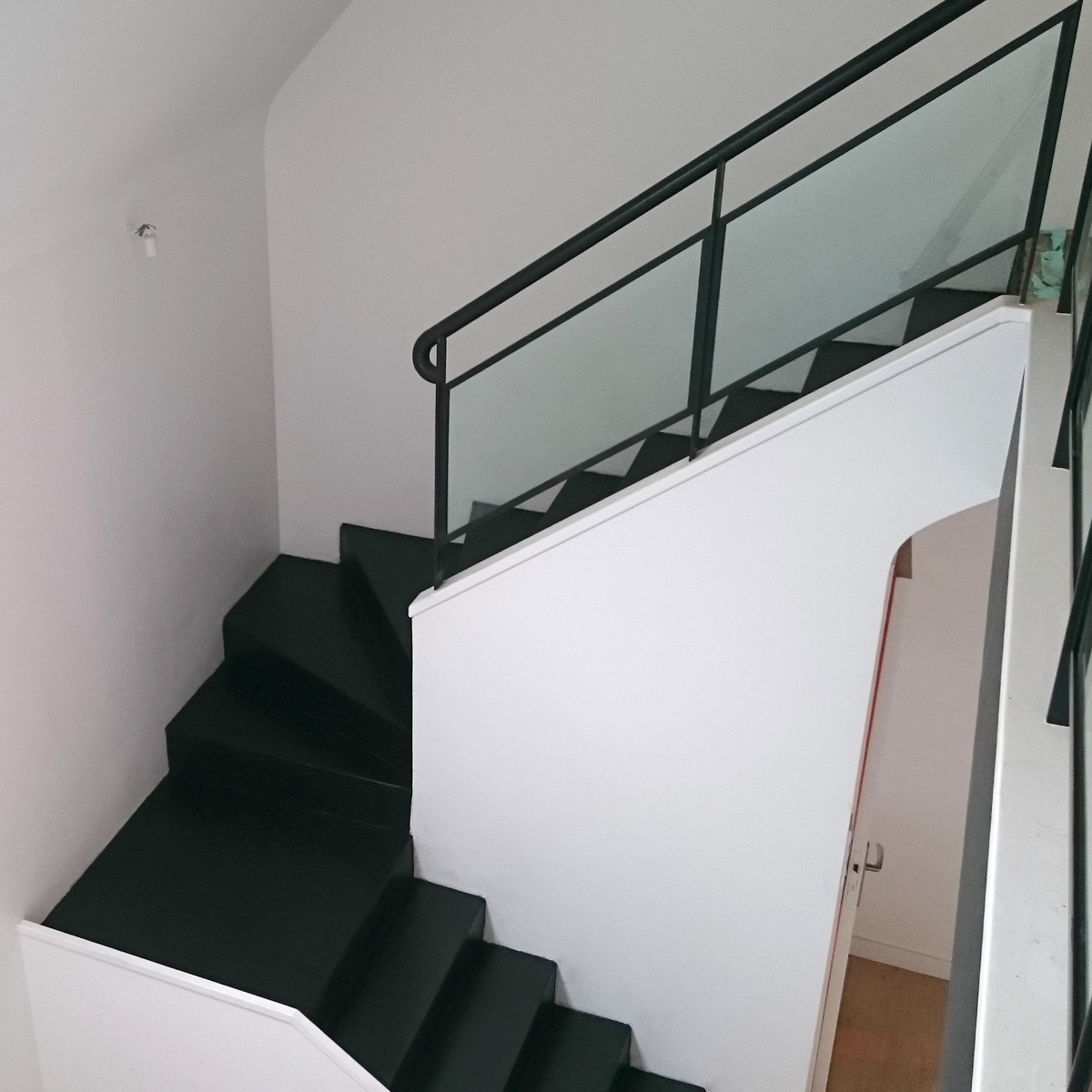Escalier moderne en béton ciré noir et murs blanc à Rennes.